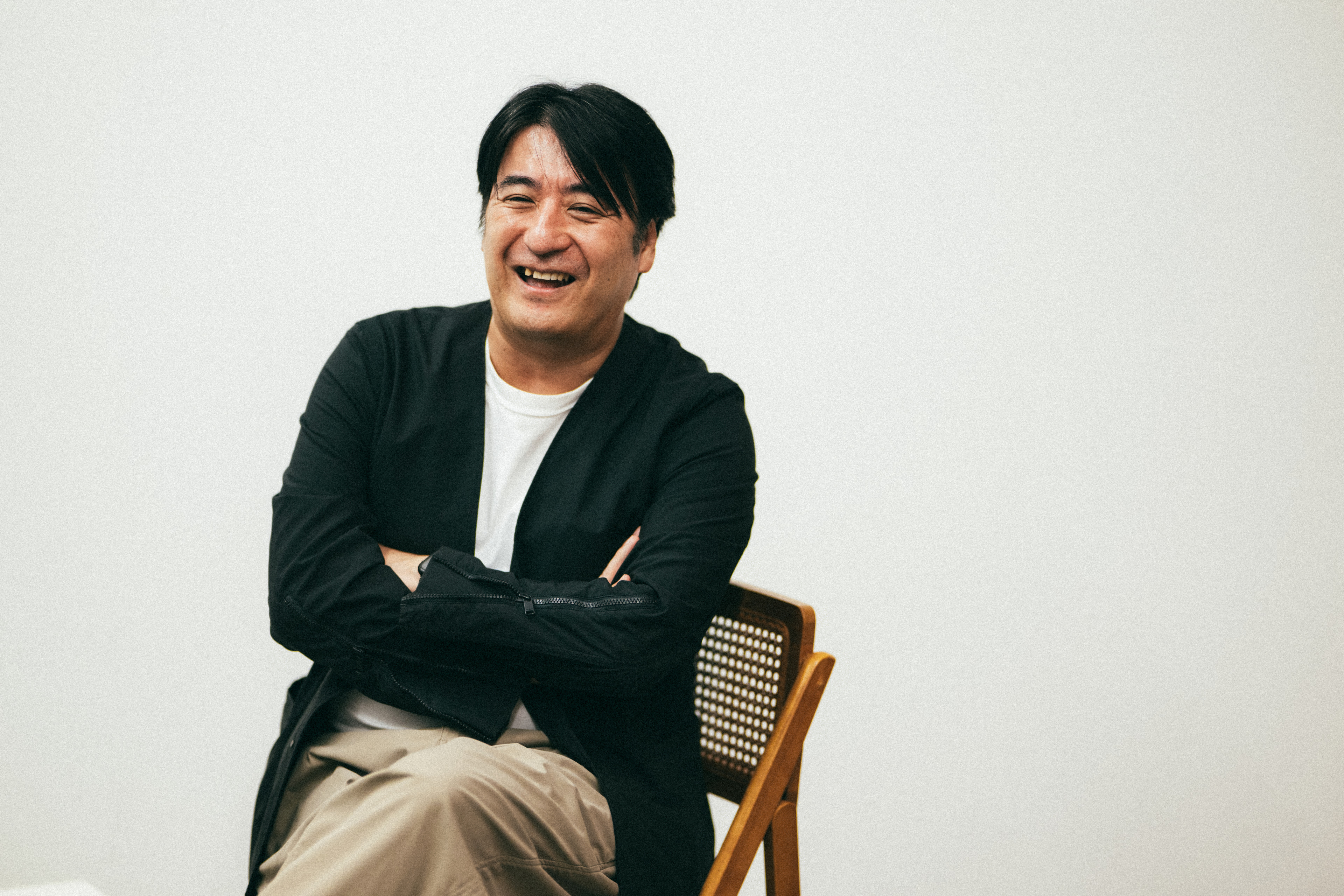 黒いジャケットに白いインナーを着て笑っている佐久間宣行さん